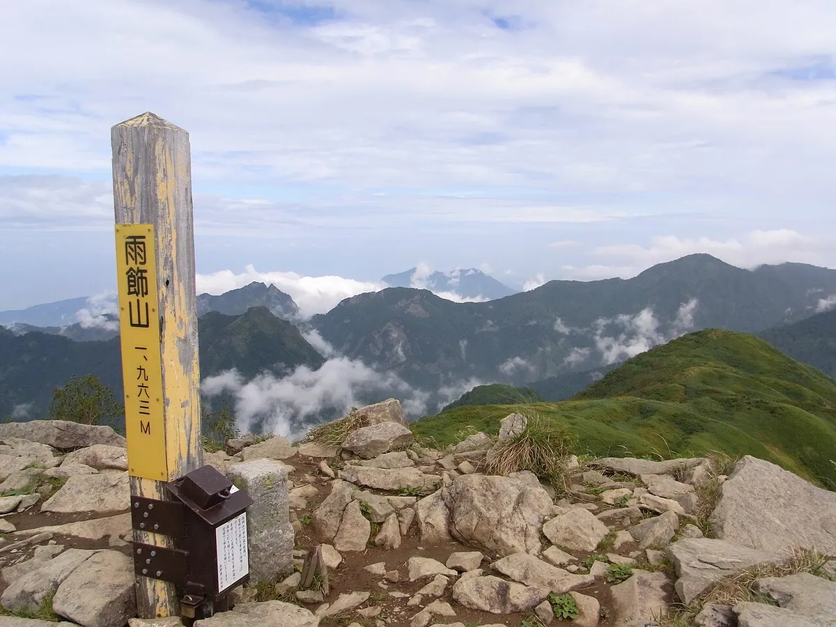 雨飾山山頂の標識と周囲の山並み