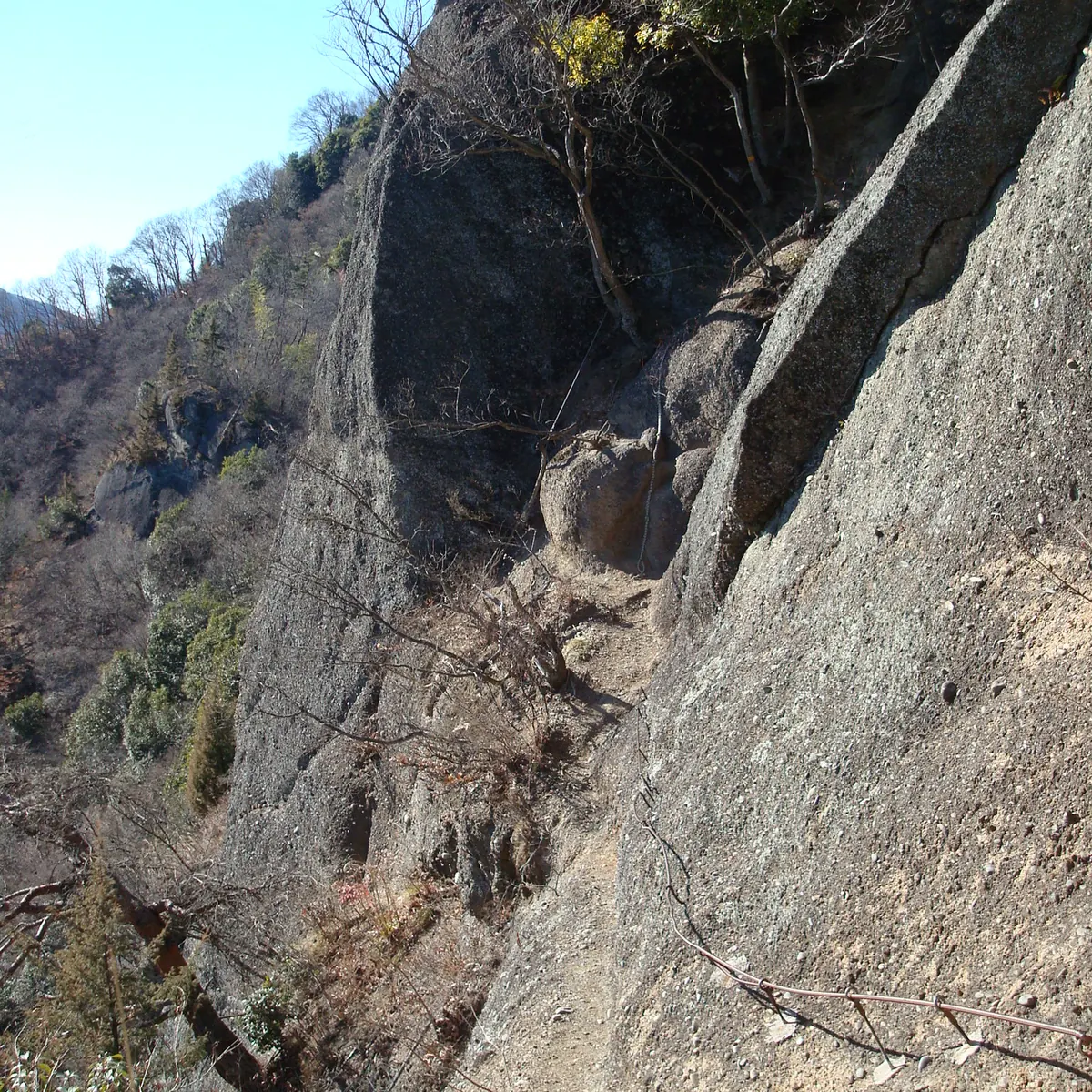 晴れた冬の日、切り立った岩壁に沿って鎖が張られている岩殿山の鎖場