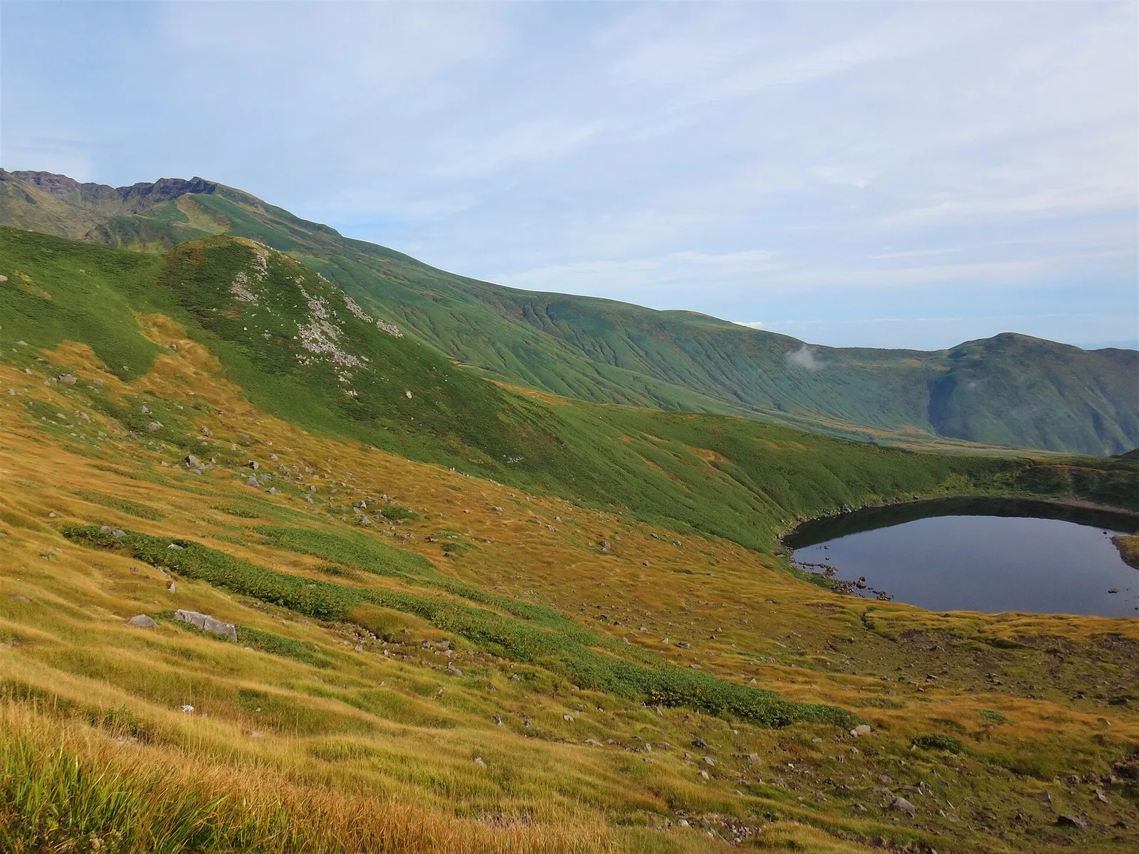 草紅葉に囲まれた秋の鳥海湖と、その奥に続く鳥海山の山肌