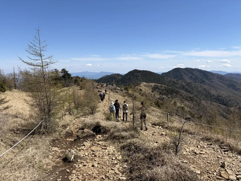 ロープが張られた草原の稜線を、大菩薩峠方面へ歩く登山者たち