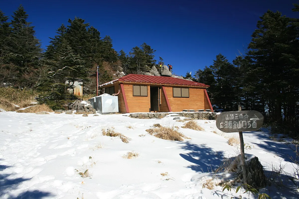 雪の積もる恵那山の山頂近くの避難小屋と標識
