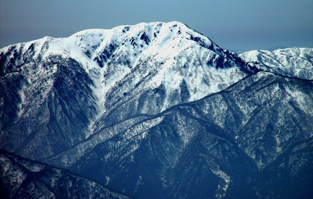 雪が残る荒島岳の山頂部と、深い谷に落ちる尾根