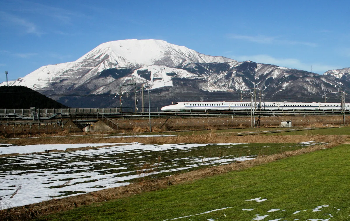 雪をかぶった伊吹山と、その手前を走る新幹線