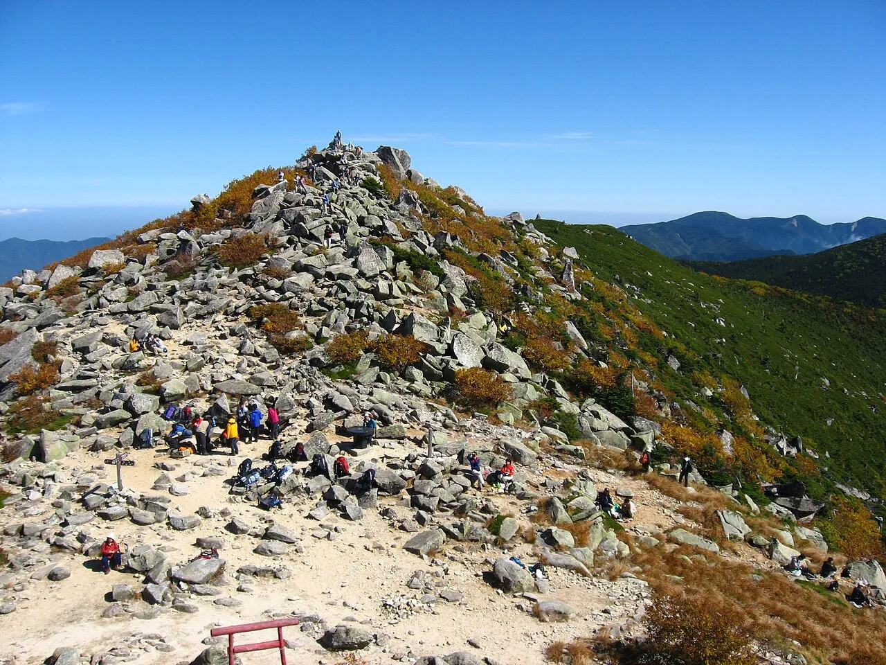 岩がちな金峰山の山頂付近の稜線と、遠くに広がる山並み