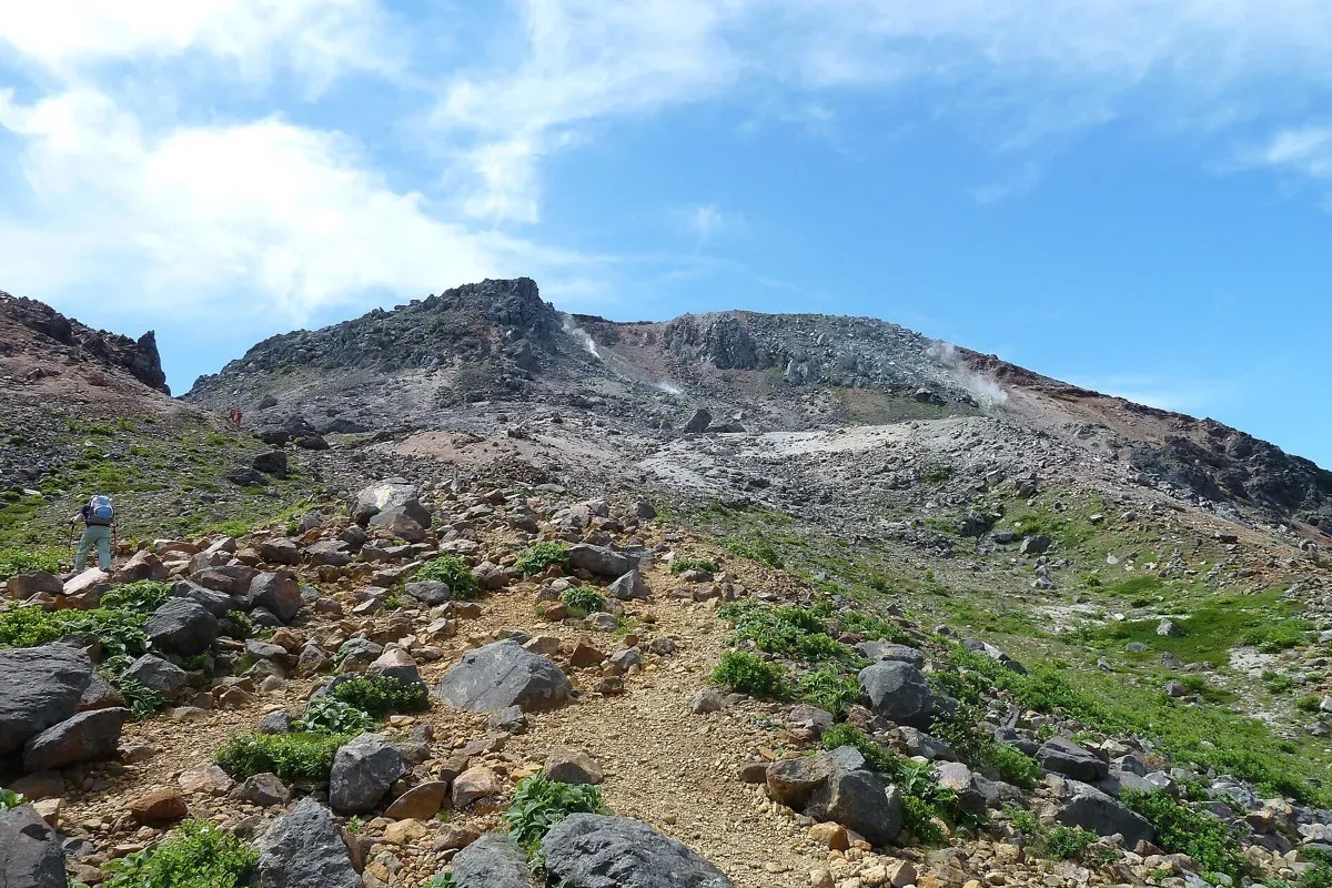 峰の茶屋の上から見た、岩が転がる登山道と茶臼岳の山頂方向