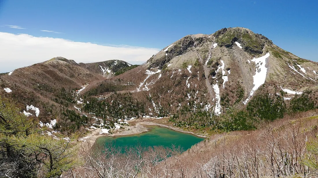残雪の岩稜と山麓の五色沼が見える日光白根山