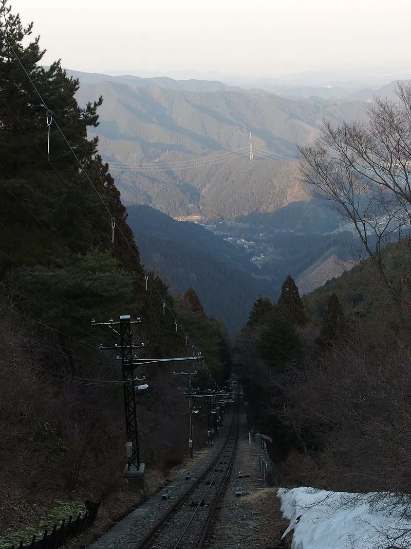 御岳山のケーブルカーの線路を上から見下ろした様子。奥に山並みが広がる
