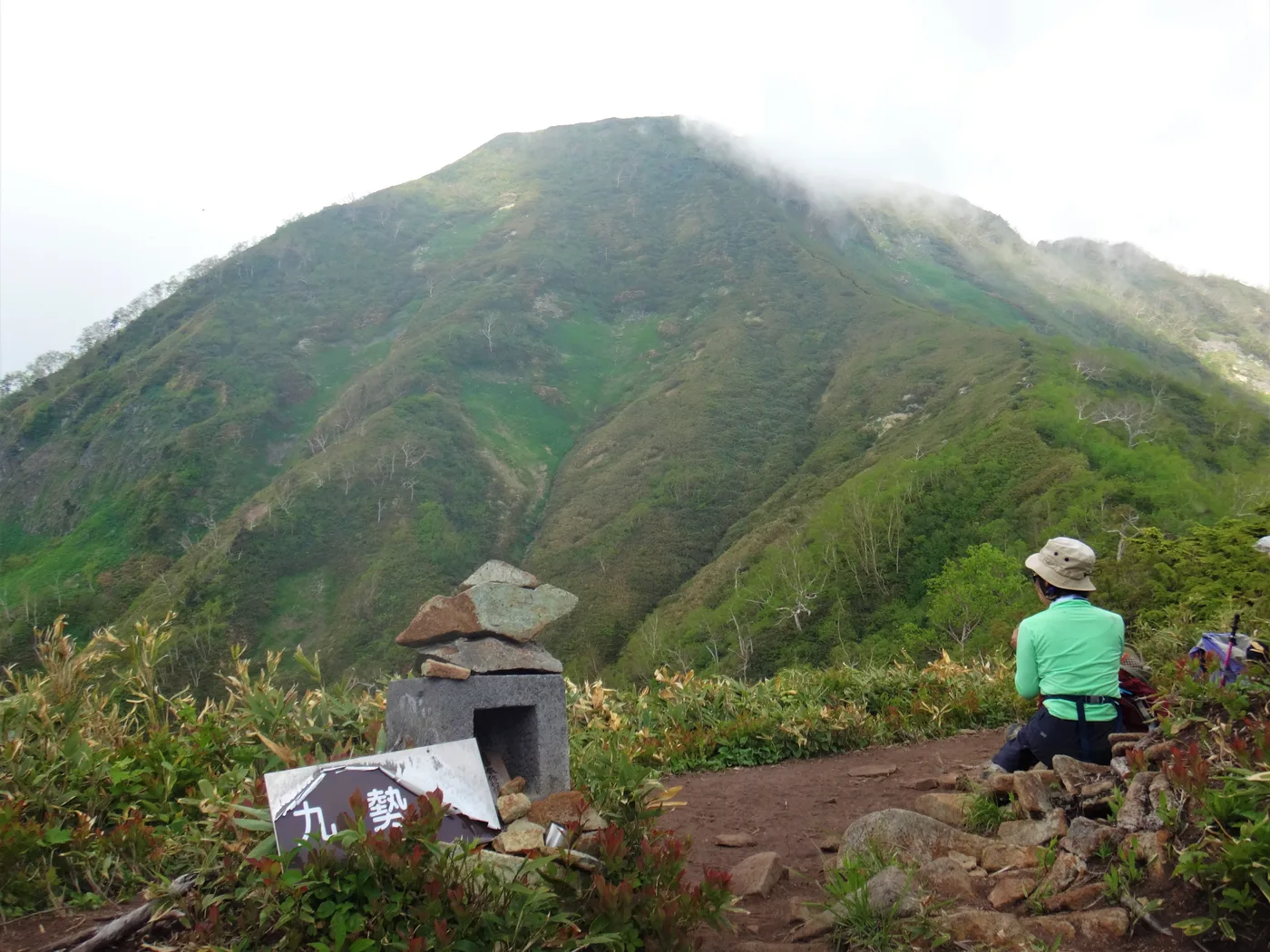 九勢至付近の稜線から見上げる、緑に覆われた高妻山の山頂部と道ばたの石仏