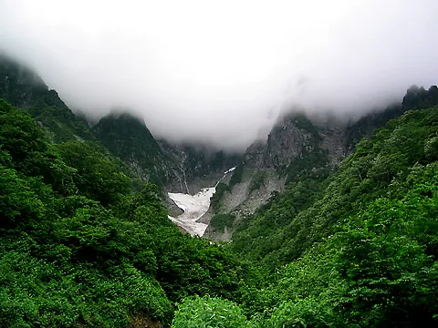 雲に覆われた谷川岳一ノ倉沢の岩壁と残雪